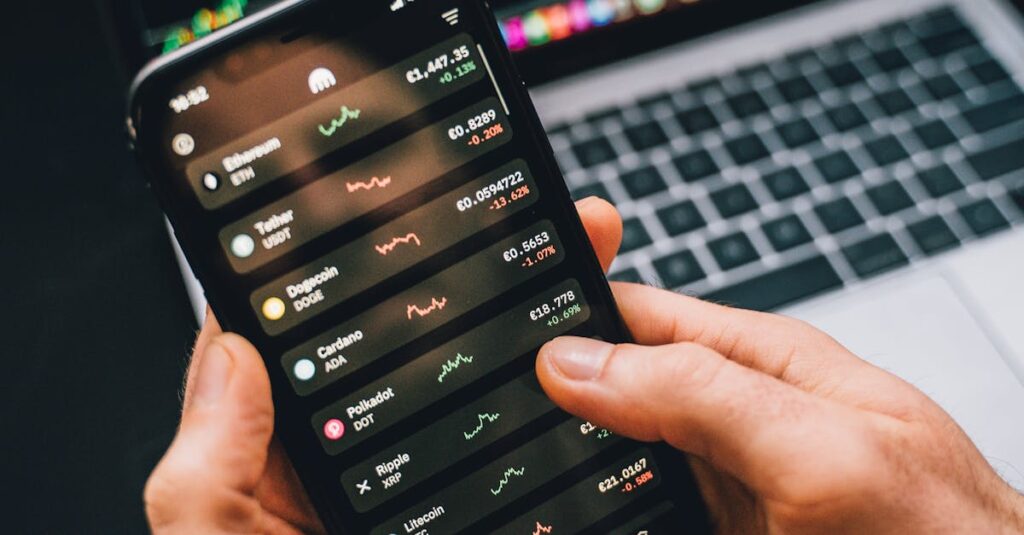 Hands holding smartphone with stock app, laptop displaying charts. Perfect for financial and technology themes.